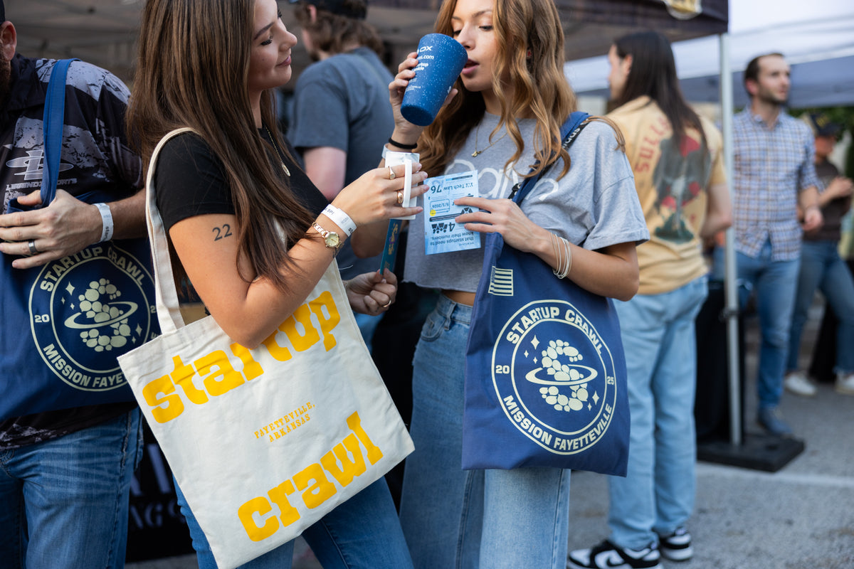 Attendees at Startup Crawl carrying cream and navy event tote bags.
